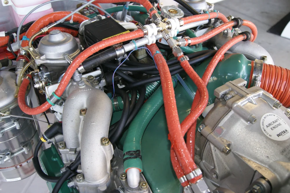 Installed ROTAX engine compartment showing multiple rubber fuel, cooling, intake, and support hoses